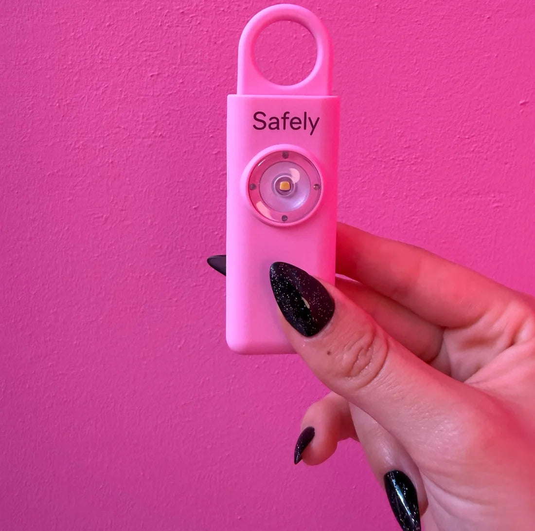 Safely ורודה מוחזקת ביד על רקע קיר ורוד